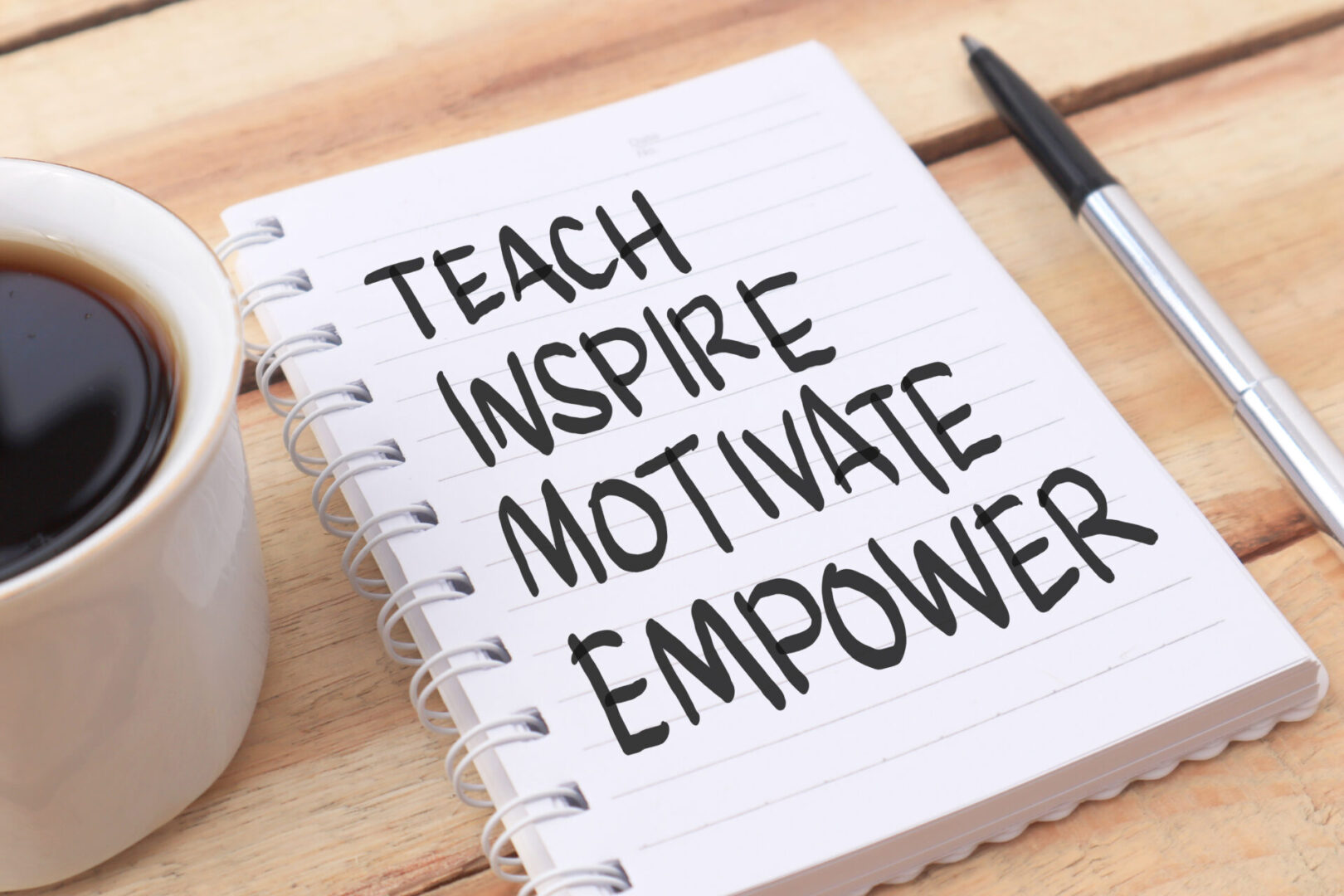 Teach inspire motivate empower, text words typography written on paper against wooden background, life and business motivational inspirational Notebook with words: Teach, Inspire, Motivate, Empower.